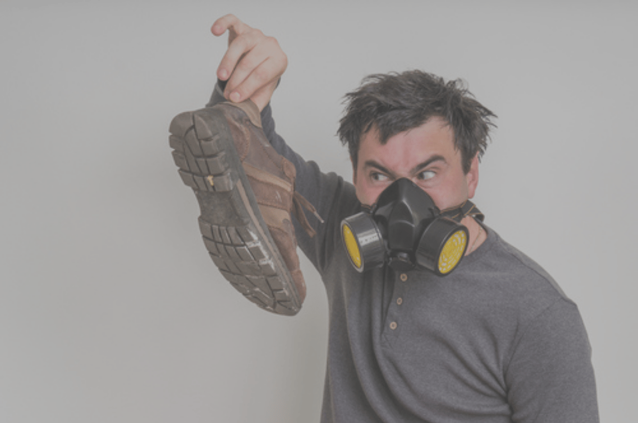 Man holding shoes with strong athlete's foot smell Man holding shoes with strong athlete's foot smell